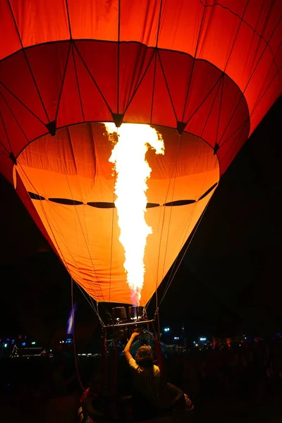 Hombre llenando el globo naranja con aire caliente. Vista de la llama i —  Fotos de Stock