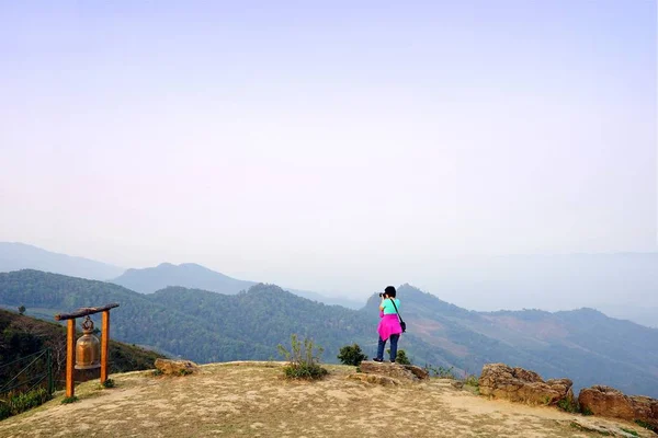 Femme tenant caméra et debout sur le sommet de la montagne regardant — Photo