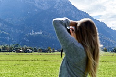 Turist Neuschwanstein kalesinin fotoğraflarını çekiyor.