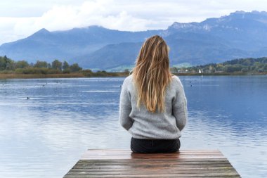 Göle bakan iskelede bir kadın.