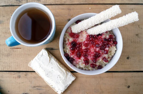 Colazione sana, vegetariana. Farina d'avena con mirtilli rossi, panino con crema di formaggio, bastoncini di cocco, tè . — Foto Stock