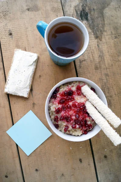 Colazione sana, vegetariana. Farina d'avena con mirtilli rossi, panino con crema di formaggio, bastoncini di cocco, tè . — Foto Stock