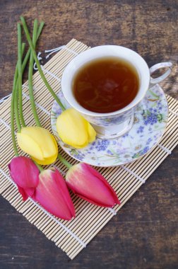 Çay bardağı, Lale çiçek, ahşap arka plan üzerinde. Bahar kompozisyon.