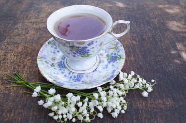 Buket çiçek ve ahşap bir tabloda çay