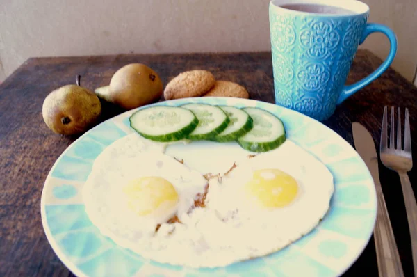 Healthy breakfast, fried eggs, cucumber, fruit, tea — Stock Photo, Image