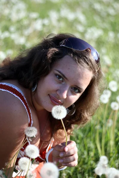 Jovem mulher em um campo com muitos dentes de leão — Fotografia de Stock