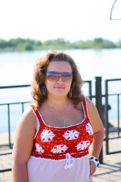 Молода жінка в сонцезахисних окулярах біля ставка в сонячний день — стокове фото