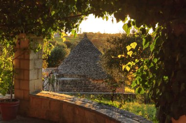 İtalya manzara: Apulia kırsal. Valle d'Itria, Cisternino bölge. Hills zeytin ağaçları ve kırsal Apulia manzara örneği Trullo.Typical. Gün batımında Portico bakan manzara.
