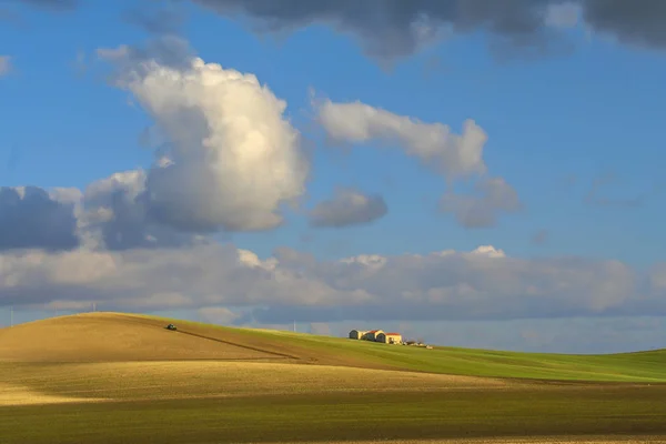 Hügelige ländliche Landschaft. Zwischen Apulien und Basilikata. Ackerfeld mit Traktor, der von Wolken dominiert wird. -Italien- — Stockfoto