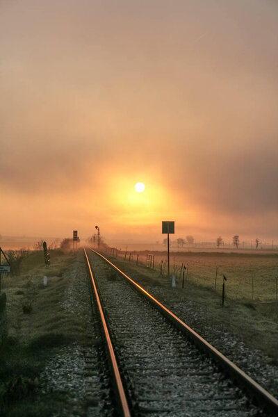 Зимний восход солнца отражается на железной дороге. Начало нового дня потеряно в точке исчезновения железных дорог. Италия, Апулия
.