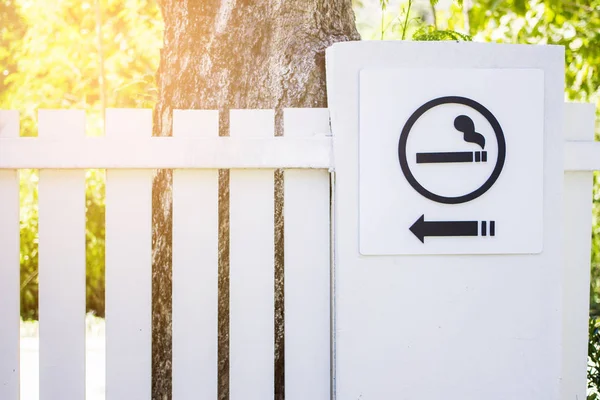 Outdoor smoking area sign on white fence