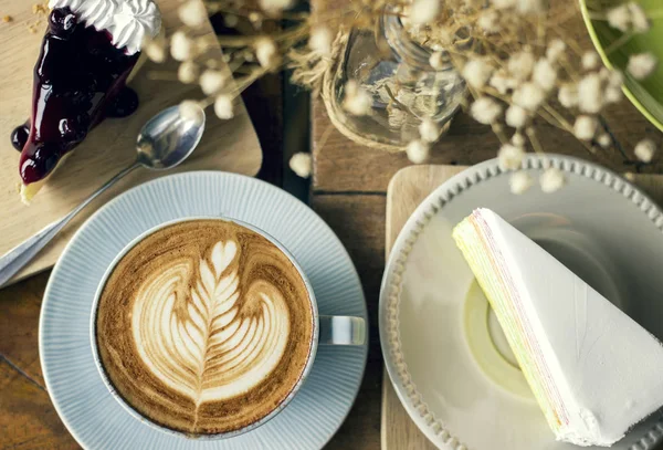 Кава капучино з латте мистецтвом та десертами для скибочок торта — стокове фото