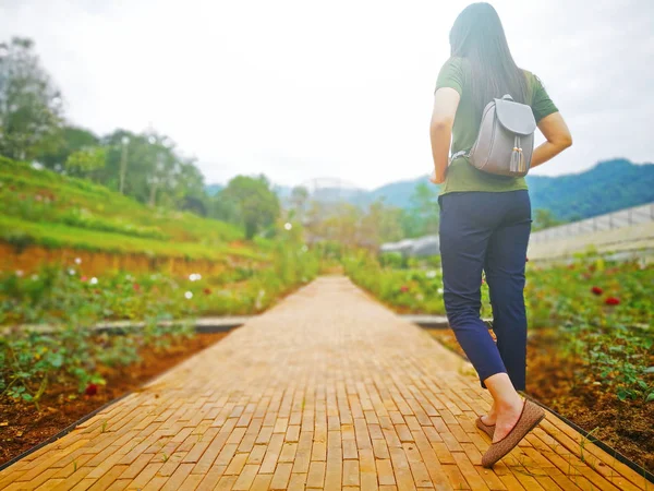 Tuğla yolu çiçek bahçede yürüyen kadın