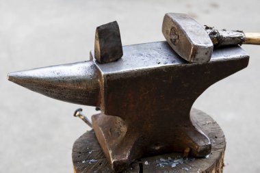Örsün üzerinde çekiç ve metal bir nesne. Demircinin demirci dükkanında kullandığı aletler ve metal eşyalar..
