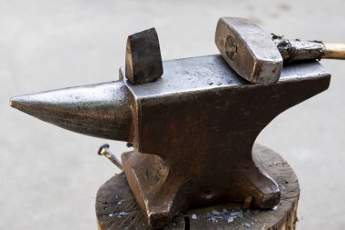 Örsün üzerinde çekiç ve metal bir nesne. Demircinin demirci dükkanında kullandığı aletler ve metal eşyalar..