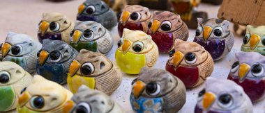 Seramikten yapılmış parlak renkli şanslı baykuşlar. Panoramik formatta fotoğraf. Asturias, İspanya