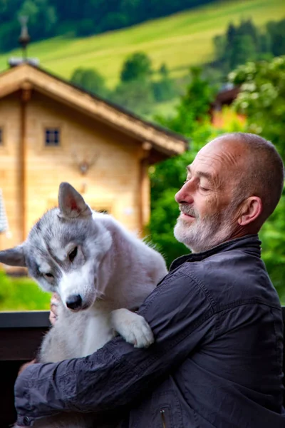 El viejo juega con su perro Husky siberiano. Estilo de vida. Recreación activa. Paisaje alpino . —  Fotos de Stock