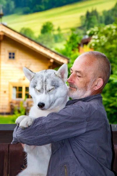 El viejo juega con su perro Husky siberiano. Estilo de vida. Recreación activa. Paisaje alpino . —  Fotos de Stock