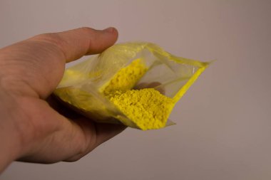 Elinde sarı şeffaf bir paket holi boyar.