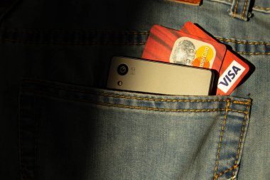 Donetsk, Ukrayna, 17 Ekim 2019: Kredi kartları ve modern telefon kot pantolonun cebinde. Dijital para kavramı.