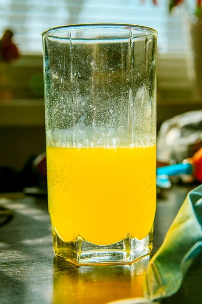 Glass of fizzy yellow vitamins drink near the medical blue mask. Illness prevention and health care concept