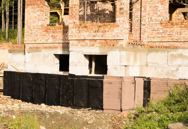 Construction techniques for waterproofing basement and foundations. Insulation material on the basement concrete wall. At construction site . House energy saving. Waterproofing house foundation with spray on tar.