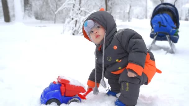 Χαριτωμένο παιδί που παίζει με το χιόνι — Αρχείο Βίντεο