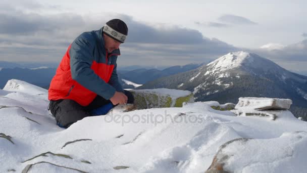 Caminante inicia fuego en las montañas nevadas — Vídeo de stock