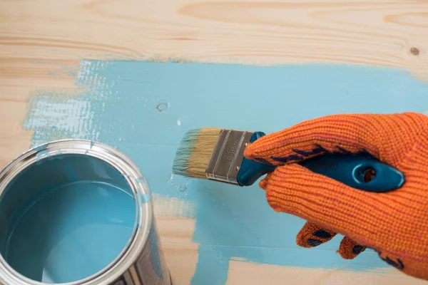 worker paints board blue paint. concept of repair, copy space, space for text. the employee paints the a wooden table