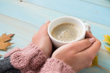 WOMANS süveterli kahve mavi ahşap masa üzerinde tutan eller. Tatil kavramı. Bir fincan kahve ahşap antika arka plan - kış zaman kavramı üzerinde tutan kız. Kahve fincanı