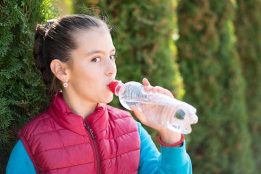 İçme suyu sıcak güneşin parkta güzel bir kızdır. Sağlıklı kavramı. Sağlıklı yaşam konsepti. kopya alanı. Portre mutlu güzel kız gülümsüyor. Portre gülümsüyor kız. Kız içme suyu