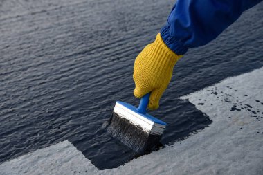 İşçi temel üzerine bitumen mastic uygular