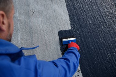 İşçi temel üzerine bitumen mastic uygular