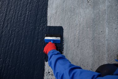 İşçi temel üzerine bitumen mastic uygular