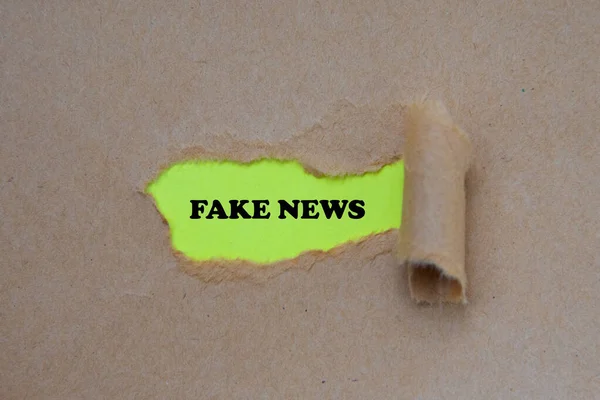 Fake news word written under torn paper