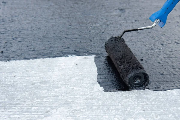 İşçi temel üzerine bitumen mastic uygular