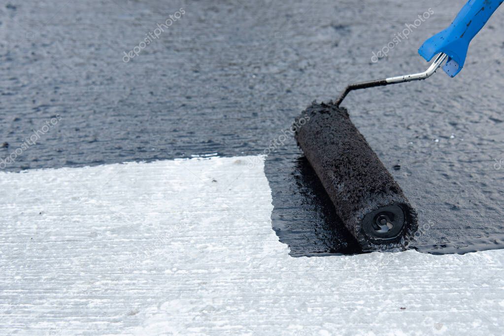 Worker applies bitumen mastic on the foundation