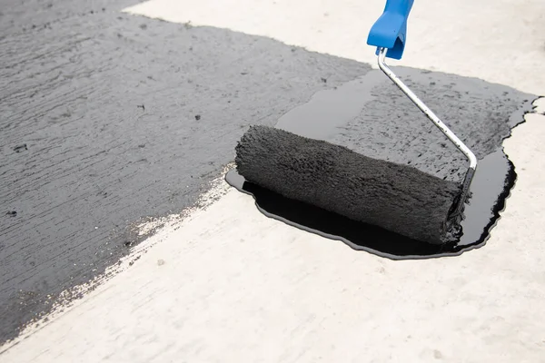 Werknemer brengt bitumen mastiek aan op de fundering — Stockfoto