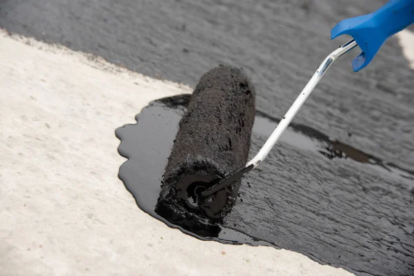 Werknemer brengt bitumen mastiek aan op de fundering — Stockfoto