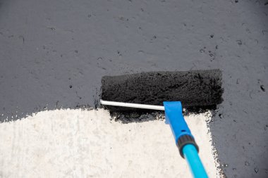 Worker applies bitumen mastic on the foundation clipart