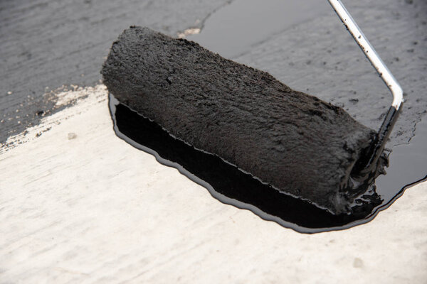 Worker applies bitumen mastic on the foundation
