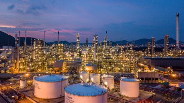 Alacakaranlıkta petrol depolama tankı ve petrokimya fabrikası endüstriyel arka planına sahip petrol rafinerisi, alacakaranlıkta hava manzaralı petrol ve gaz rafinerisi.