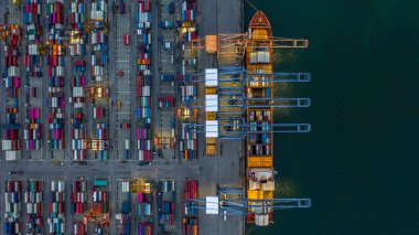 Gece endüstriyel limanda hava görüntülü konteyner gemisi, endüstriyel vinçli konteyner kargo gemisi, geceleri ithalat ve ihracat yapan konteyner gemisi..