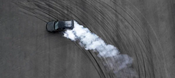 空中トップビュープロのドライバーは アスファルトの道路トラック上で黒い車を漂流します 煙の多くと抽象アスファルトの道路タイヤスキッドマーク上の自動車や自動車レースカードリフト 上からの眺め — ストック写真