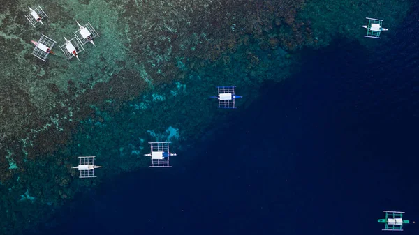 Aerial top down view of boat moving in open sea with clear and turquoise water on over coral reef,  Boat left the tropical lagoon, Moalboal, Oslob, Cebu Island, Philippines.