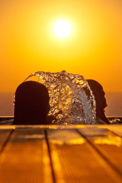 Filles de natation silhouettes et éclaboussures d'eau contre la mer à su — Photo