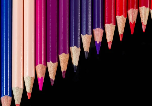 Color pencils in diagonal formation isolated on black warm palet — Stock Photo, Image