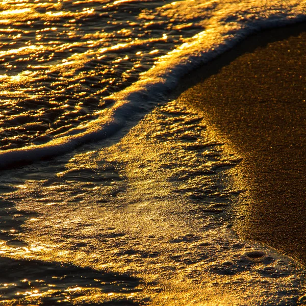 Abstracte vormen van het breken van golven op zanderige oever bij zonsondergang — Stockfoto