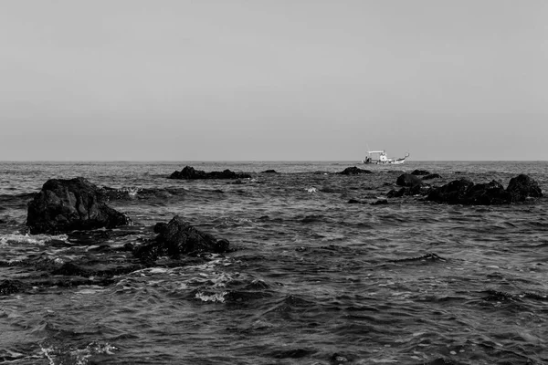 Rocky seashore and passing boat in Pomos, Cyprus in monochrome — Stock Photo, Image