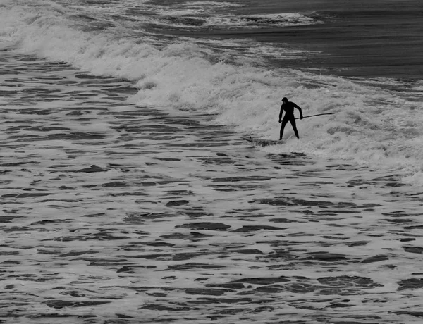 Surfer κρατώντας κουπί σε στολή διαπραγμάτευση κύματα σε Tynemouth να — Φωτογραφία Αρχείου
